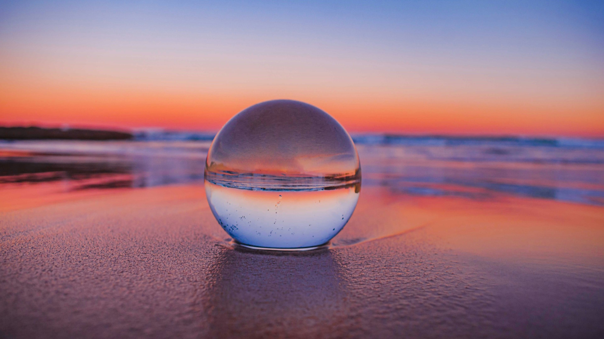 Photo of crystal ball on a beach at sund down