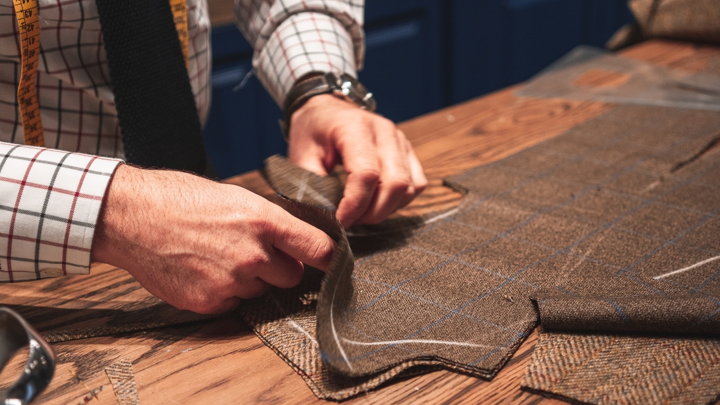 Photo of a tailor carefully chalking preparing a bespoke suit jacket